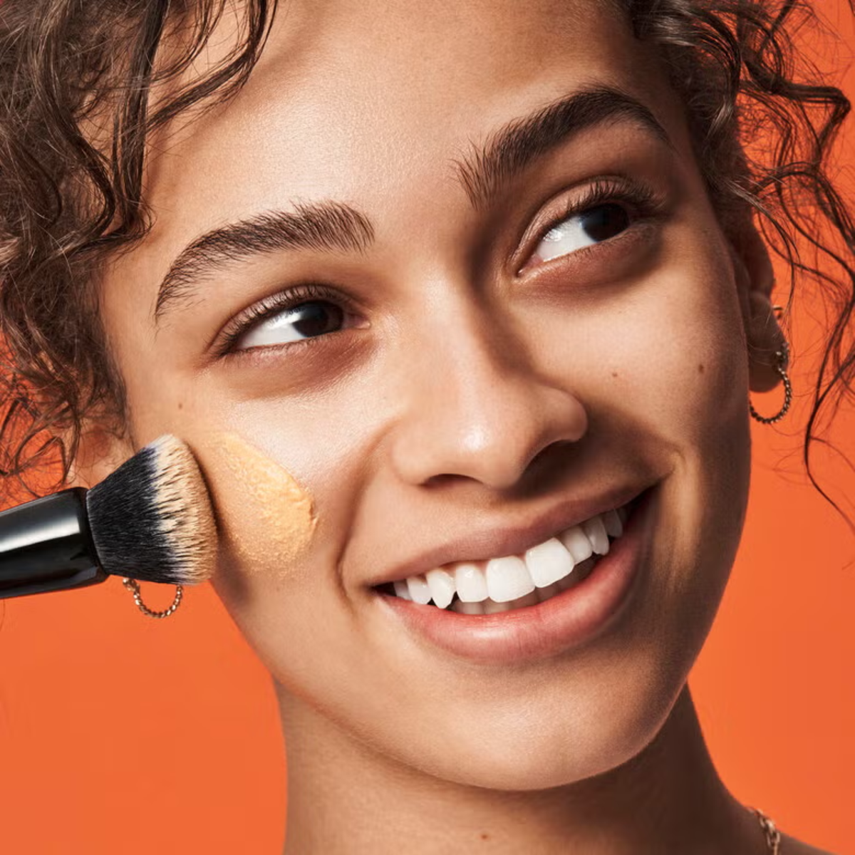 Model brengt e.l.f. C-Brightening Putty Primer aan voor een stralende make-upbasis.