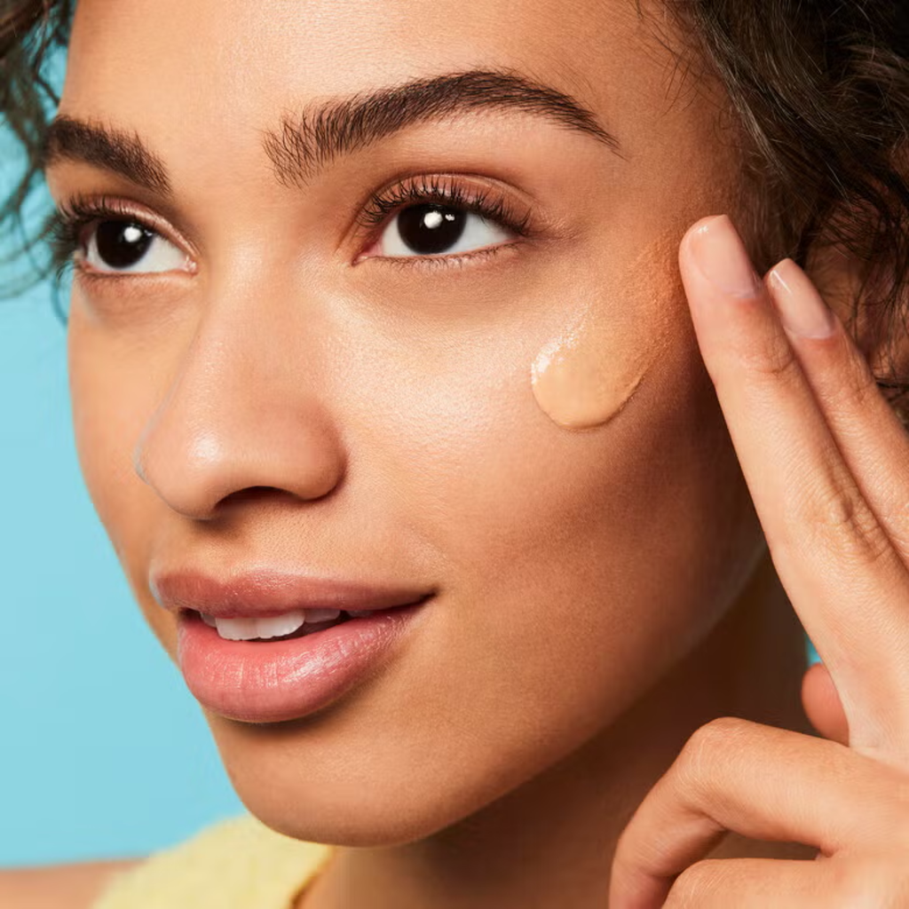 Model brengt e.l.f. Suntouchable! Whoa Glow SPF 30 aan voor een stralende huid.