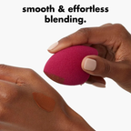 Hand gebruikt de roze e.l.f. make-upspons om make-up op de hand te blenden.